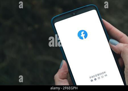 Podolsk, Ukraine - March 29, 2021: Woman hand is pressing the Facebook screen on android smartphone, Social media are using for information sharing Stock Photo