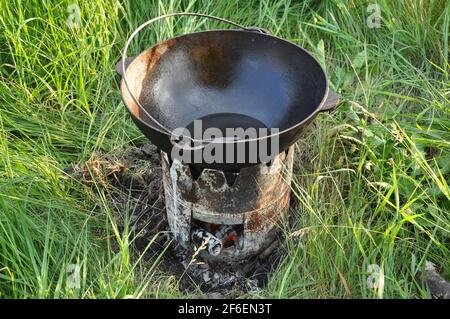 Cauldron on fire outside at summer time. Traveling, tourism, picnic cooking, cooking at the stake in a cauldron, fire and smoke. Stock Photo