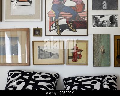 Artistic bedroom in a loft house in Milano, Italy. Detail of the wall behind the bed with several framed artworks and prints and pictures Stock Photo