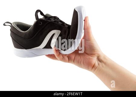 human hand bending lightweight black airmesh summer walking shoes isolated on white background. Stock Photo