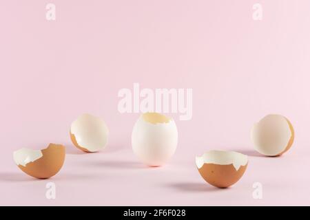 Cracked eggshell with broken Easter eggs against pastel pink background. Easter minimal concept. Creative Happy Easter or spring layout. Stock Photo