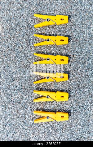 A few yellow clothes clips in a raw on grey background Stock Photo