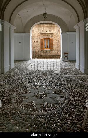 Covered passage with pavé floor and decorations on the floor of a compass rose in a circle. Penne, Pescara province, Abruzzo, Italy, Europe Stock Photo