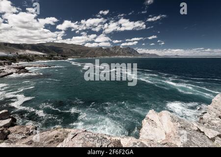 Scenic view of Hermanus and Walker Bay from cliff path near Cape Town, South Africa against blue sky with clouds Stock Photo