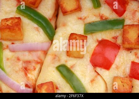 Pizza Paneer Makhani , home made delicious  pizza  made using red and green bell pepper ,onion ,mozzarella cheese and thin pastry crust slices ,closeu Stock Photo