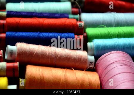 Colorful spools of sewing threads in closeup view. pink, peach, blue, yellow and green colors. selective focus. high angle view. sewing and hobby. Stock Photo