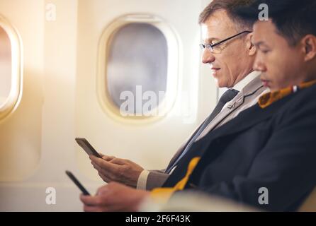 Man travelling by plane and using mobile phone, concept Internet in air stratosphere Stock Photo