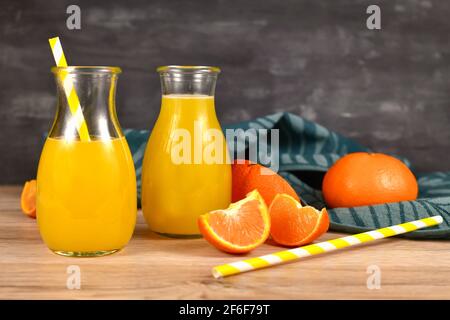Lemonade made from citrus fruits in small bottle jars with drinking straws and fruit slices on wooden table Stock Photo