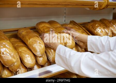 Quality control of bread products by an inspector in a supermarket. Stock Photo