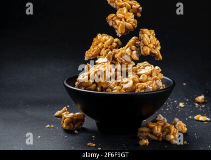 Peanut kozinaki falling in bowl on black background Stock Photo