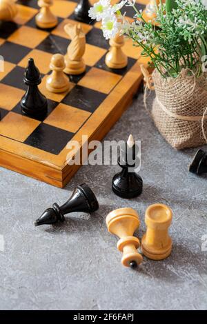 Chess. Chess board, chess pieces and flowers on a gray-blue background on a sunny day Stock Photo