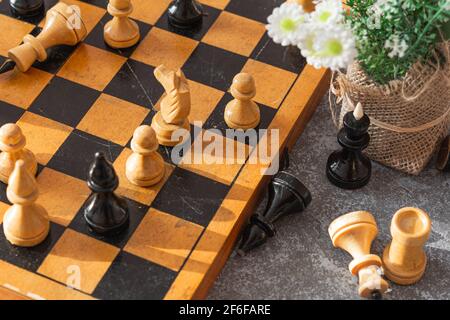 Chess. Chess board, chess pieces and flowers on a gray-blue background on a sunny day Stock Photo