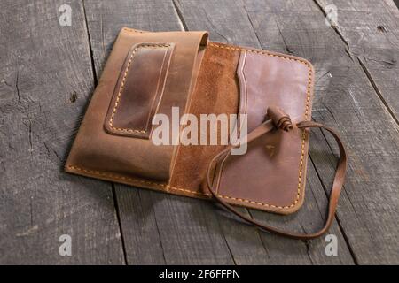 Hand made leather brown tobacco-pouch on wood background. DIY Stock Photo