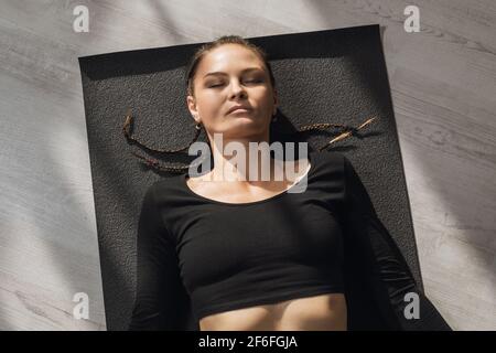 Woman practicing yoga, resting after training, performing shavasana exercise, top view. Stock Photo
