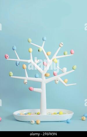 Small decorative tree with colorful quail eggs on branches; Easter background with copy space Stock Photo