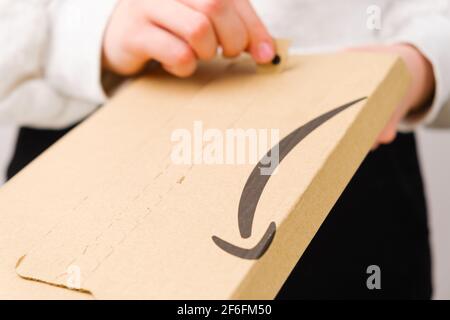 Close up woman hands opening a parcel from Amazon, March 2021, Prague, Czech Republic Stock Photo