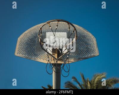 A low angle shot of a basketball hoop against a blue sunny sky Stock Photo