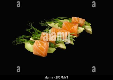 Roll with salmon, avocado, microgreen. Isolated over black background. Stock Photo