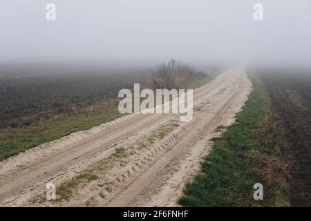sandy ground path through a field in fall season hidden in a fog Stock ...