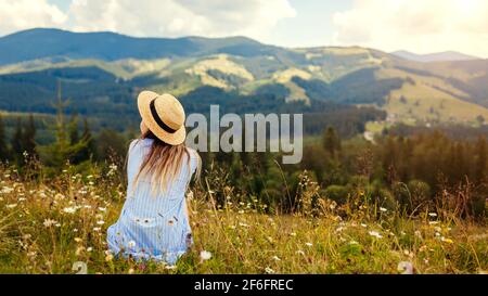Traveling in spring Ukraine. Trip to Carpathian mountains. Woman traveler relaxing in flowers admiring landscape view Stock Photo