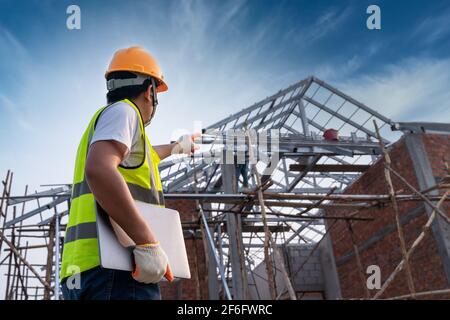Engineer technician Looking Up roof structure and Analyzing an Unfinished Construction Project Stock Photo