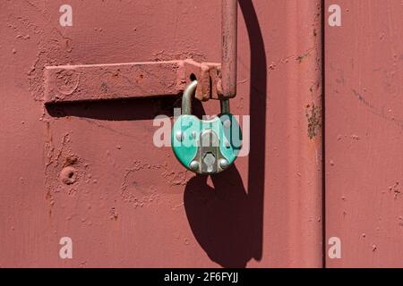 Old rusted grungy metal garage door with latch and padlock. Close up of rusty vintage lock on closed door Stock Photo