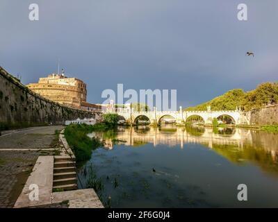 Castel Sant'Angelo cylindrical castle and marble St. Angelo Bridge epic scenic with water reflection view from river Tiber embankment in Rome, Italy Stock Photo