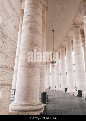 White marble colonnade with chandelier near landmark St. Peter's Square (Piazza San Pietro). Vatican City, Italy. Vertical view Stock Photo