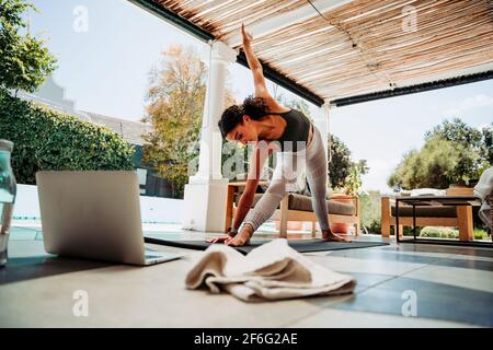 Mixed race female stretching legs practicing yoga outside home  Stock Photo