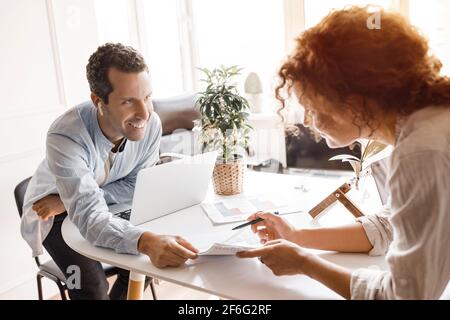 Stylish happy confident colleagues discussing a new project together in modern office, smiling. Successful business partners working on strategy for Stock Photo