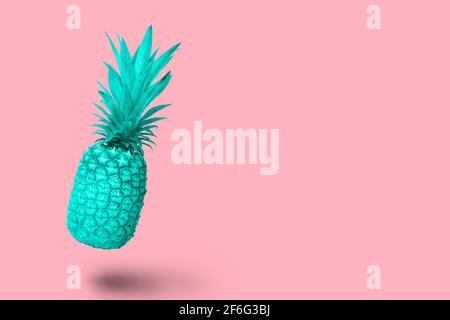 Design turquoise blue pineapple fruit floating on a pink background Stock Photo