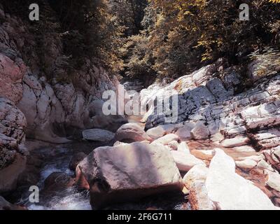 Large light stones in the river flowing into the gorge between the relief canyons on a sunny day Stock Photo