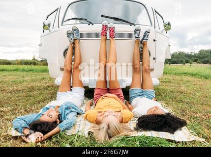 Three women lying on a blanket in front of a van Stock Photo