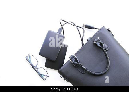 Composition with black bag, external hard disks and glasses on white background. Business details. Stock Photo