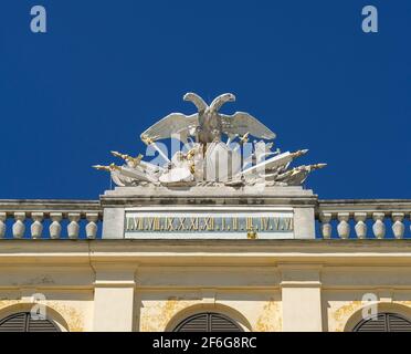 Schonbrunn Palace Clock: Facing the garden is an elaborate double eagle decorated linear clock high above the central garden door of this Vienna landmark. Stock Photo