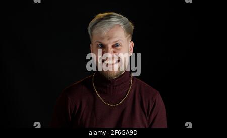 Disappointed handsome man in stylish blouse showing funny and agressive emotion on black background Stock Photo
