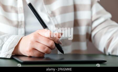 Closeup female hand designer editor or photographer use graphics tablet at home office workplace. Creative designer working with professional equipmen Stock Photo