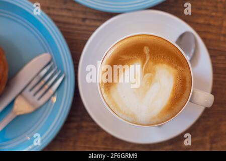 Top view Close up hot cappuccino, latte on table with blur coffee shop background. Hot cappuccino coffee on wood table with blur brakefast background. Stock Photo
