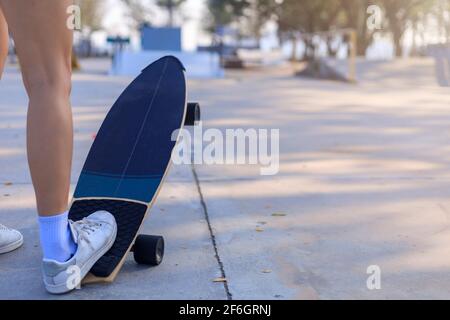 Close-up Asian women surf skate or skateboard outdoors on beautiful morning. Happy young women play surf skate at ramp park on morning time. Close up Stock Photo