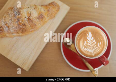 Top view Close up hot cappuccino, latte on table with blur coffee shop background. Hot cappuccino coffee on wood table with blur croissant background. Stock Photo