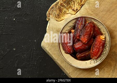 Dried dates on a wooden table in silver dishes close-up. Composition of dried dates in ramadan dish on wooden table. Stock Photo