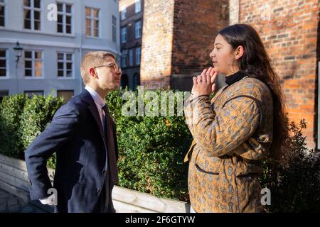 Two colleagues, man and woman discuss over a working project outdoors. Stock Photo