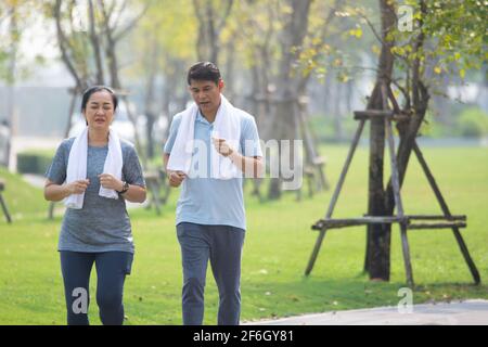 Asian middle aged couple jogging, Asian man women running jogging exercise in city park on morning Stock Photo