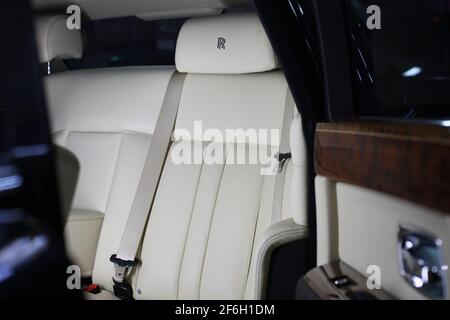 The Hand Stitched Headrest And Interior Of A 2009 Rolls Royce Phantom With White Leather And Wooden Door Trim Stock Photo