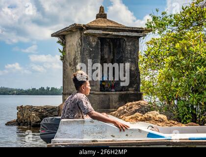 BENTOTA, SRI LANKA - 14 NOVEMBER, 2019: A local man with an exotic hairstyle near a sacred site on the Bentota Ganga river in the jungle on the island Stock Photo