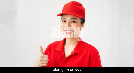 Professional asian female in cap, t-shirt working as courier or dealer, showing thumbs up gesture Stock Photo