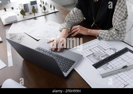 Close-up of architect typing on laptop at the table and developing new project of building working at office Stock Photo