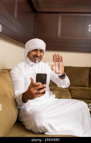 Arabian man video calling with phone at home during quarantine Stock Photo