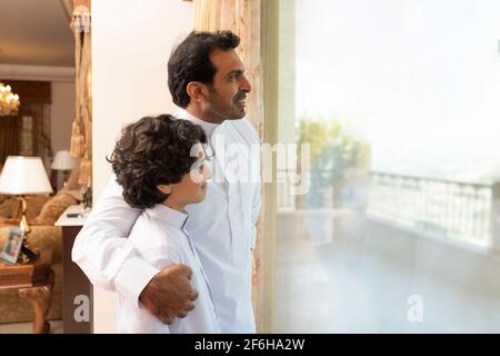 Arabian father embracing son at home  looking at the window Stock Photo