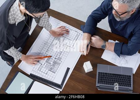 High angle view of two engineers examining project of new building at the table at office Stock Photo